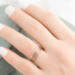  A hand with rose gold diamond-textured stacking rings, against a blurred green velvet backdrop. 

